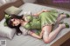 A woman in a green dress laying on a bed.