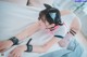 A woman laying on a bed wearing a cat ears headband.