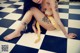 A woman with tattoos sitting on a checkered floor holding a snake.
