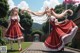 A couple of girls in red dresses walking down a sidewalk.