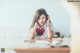 A woman sitting at a desk talking on a cell phone.