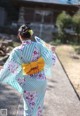 A woman in a kimono walking down a sidewalk holding a fan.