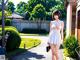 A woman in a white dress walking down a street.