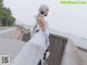 A woman in a white dress standing on a bridge.