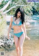 A woman in a blue bikini standing in the water.