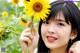 A woman holding a sunflower in front of her face.