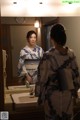 A woman in a kimono standing in front of a mirror.