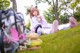 A woman laying on the grass with a backpack and a stuffed animal.